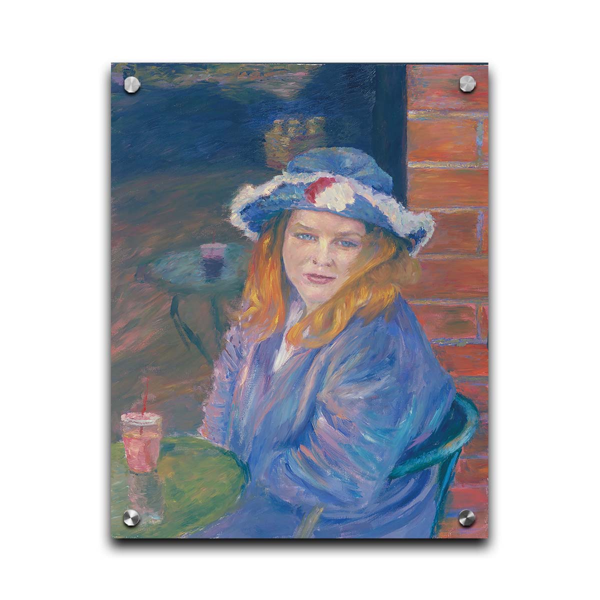 A portrait of a person in a blue outfit, sitting at a table outside a brick building with a drink. Printed on acrylic.