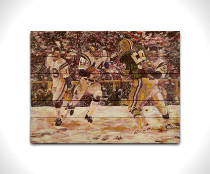 A painting of a snowy scene during the November 1977 football team between the Minnesota Vikings and the Green Bay Packers, centering on Vikings player Chuck Foreman as he runs the ball past an opponent with the help of his teammates. Printed on a wood pallet.