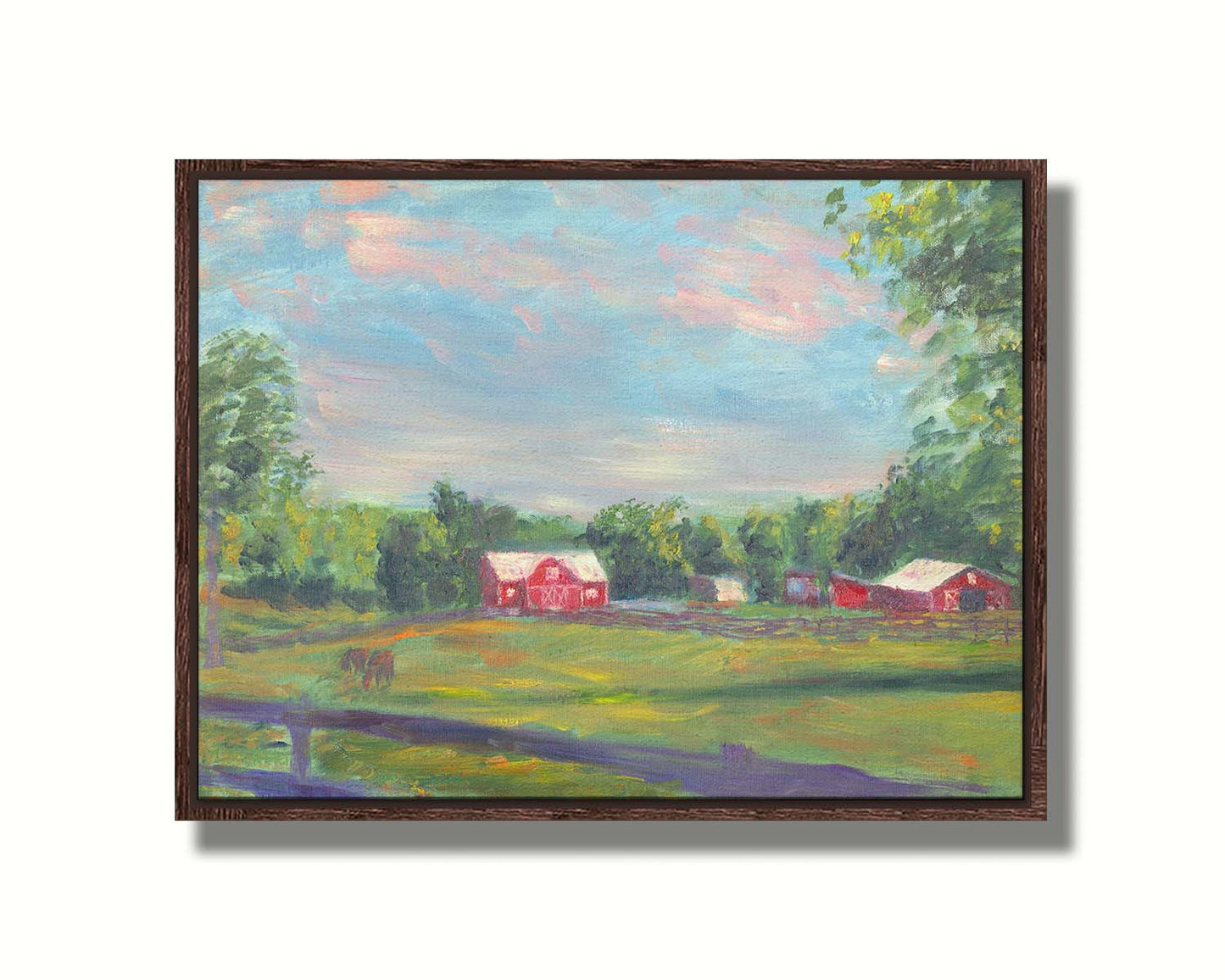 A painting of a fenced field, where horses are grazing, Red barns stand on the other side of the pasture, contrasting against the green trees behind themâ€“ all under a wide, open sky. Printed on canvas in a float frame.