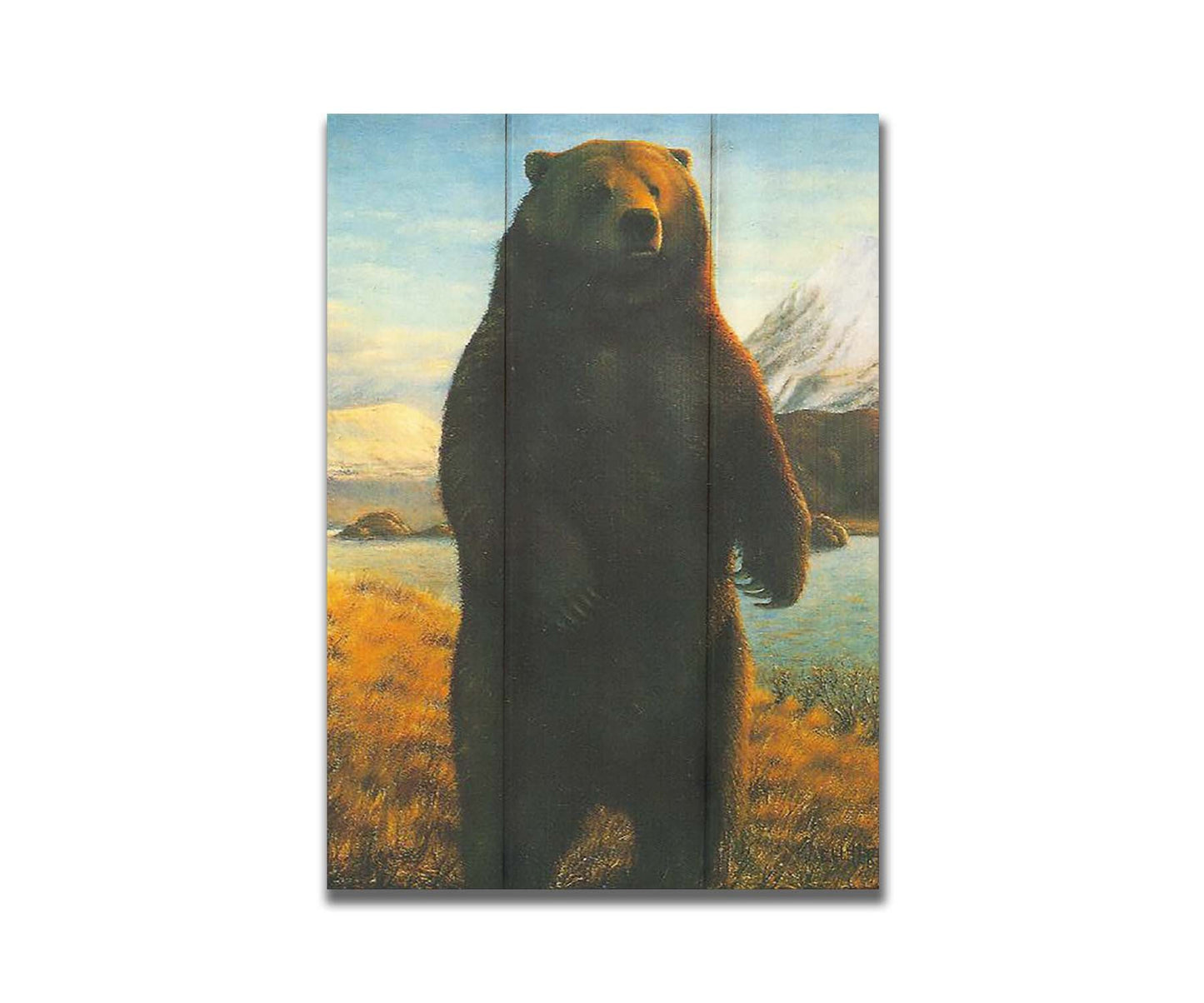 A portrait painting of a brown bear standing on its back legs in a yellow field, next to a lake and mountain range. Printed on a box board.