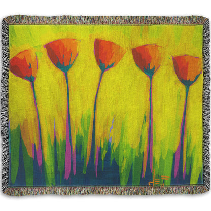 A woven throw blanket designed with a painting of five simplified red flowers against a striking yellow and green background.