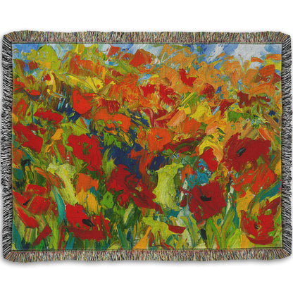 A woven throw blanket designed with a painting of a field of red and orange flowers, stylized in expressive large brushstrokes.
