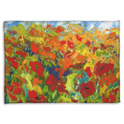 A coral fleece blanket designed with a painting of a field of red and orange flowers, stylized in expressive large brushstrokes.