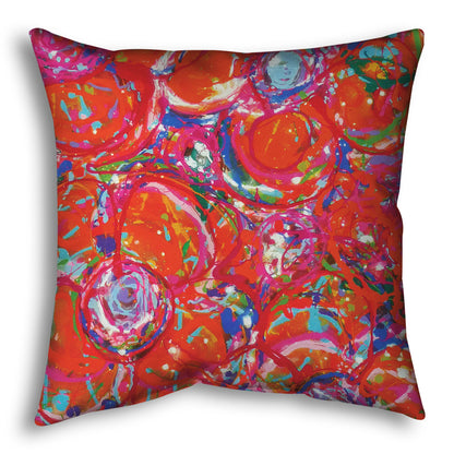 A throw pillow designed with a drip painting of a cluster of abstracted flowers created with splatters of orange, red, and pink with accents of green, blue, yellow, and purple.