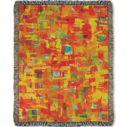 A woven throw blanket designed with a painting of an abstract organic pattern of orange, yellow, and red accented by blue, pink, green, black, and white.