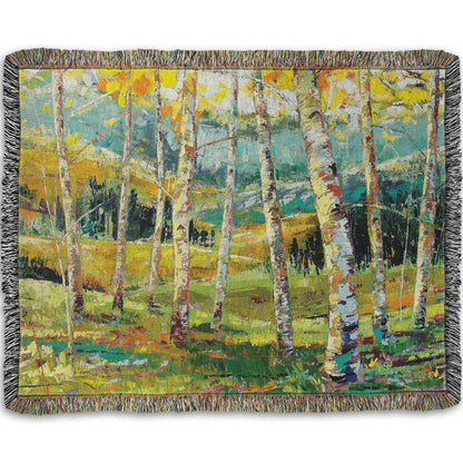 A woven throw blanket designed with an expressive painting of a birch forest with the yellow leaves of fall.
