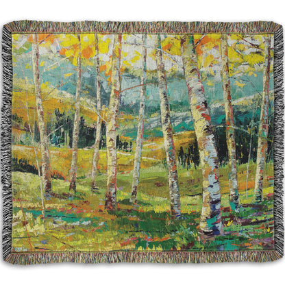 A woven throw blanket designed with an expressive painting of a birch forest with the yellow leaves of fall.