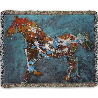 A woven throw blanket designed with a drip painting of a brown silhouetted horse accented with blue and white, against a blue background.