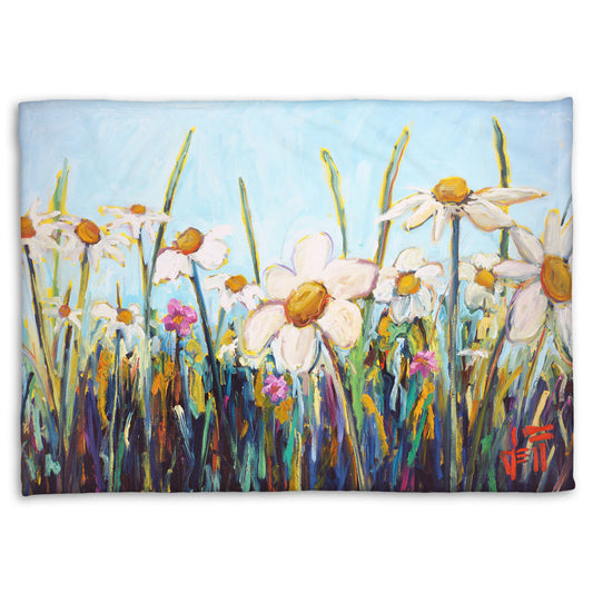 A fleece throw blanket designed with a painting of a wildflower field from a low angle, full of white daisies accented by small pink flowers.