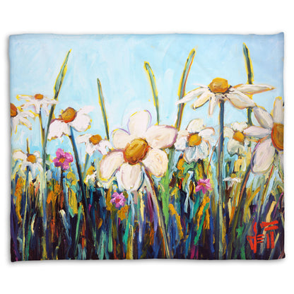 A fleece throw blanket designed with a painting of a wildflower field from a low angle, full of white daisies accented by small pink flowers.