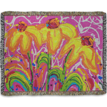 A woven blanket designed with a drip painting of three yellow wildflowers on a pink background, accented by orange, blue, green, and white.