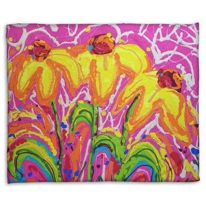 A fleece blanket designed with a drip painting of three yellow wildflowers on a pink background, accented by orange, blue, green, and white.