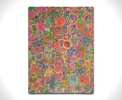 An abstract drip painting of many simplified flower shapes, utilizing a wide range of bright colors. Printed on a wood pallet.