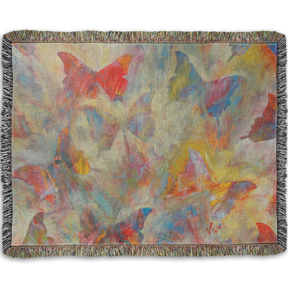 A woven throw blanket designed with an abstracted painting of a pattern of butterflies, created in an array of colors with textured brushstrokes.