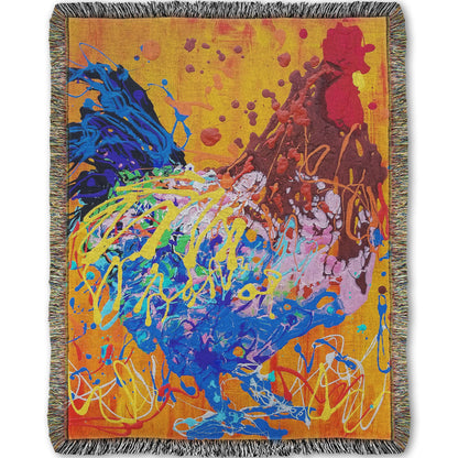 A woven throw blanket designed with a drip painting of a brown and blue rooster on a vibrant orange background, splattered with accents of yellow, white, and red. 