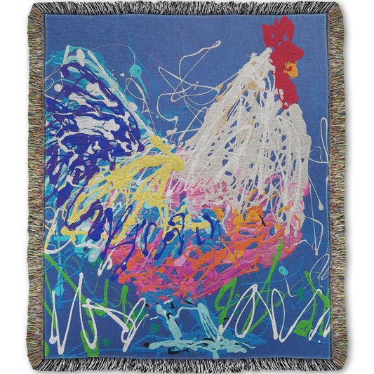 A woven throw blanket designed with a drip painting of a white and blue rooster on a gentle blue background, splattered with accents of green, white, pink, and yellow.