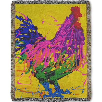 A woven blanket designed with a drip painting of a pink and purple rooster on a bright yellow background, accented with blue and green.