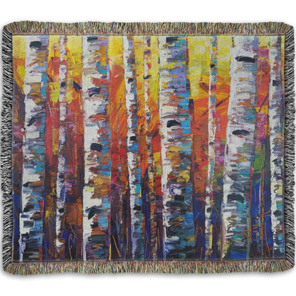 A woven throw blanket designed with a colorful painting of a forest of birch trees in arbitrary color, with white trunks against a yellow, red, and blue background made of large swaths of pallet knife paint.