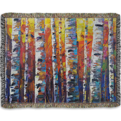 A woven throw blanket designed with a colorful painting of a forest of birch trees in arbitrary color, with white trunks against a yellow, red, and blue background made of large swaths of pallet knife paint.