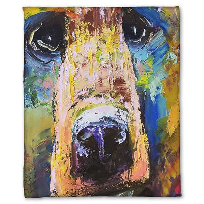 A fleece throw blanket designed with a painting of a bear's face closeup, accented with blue and yellow.