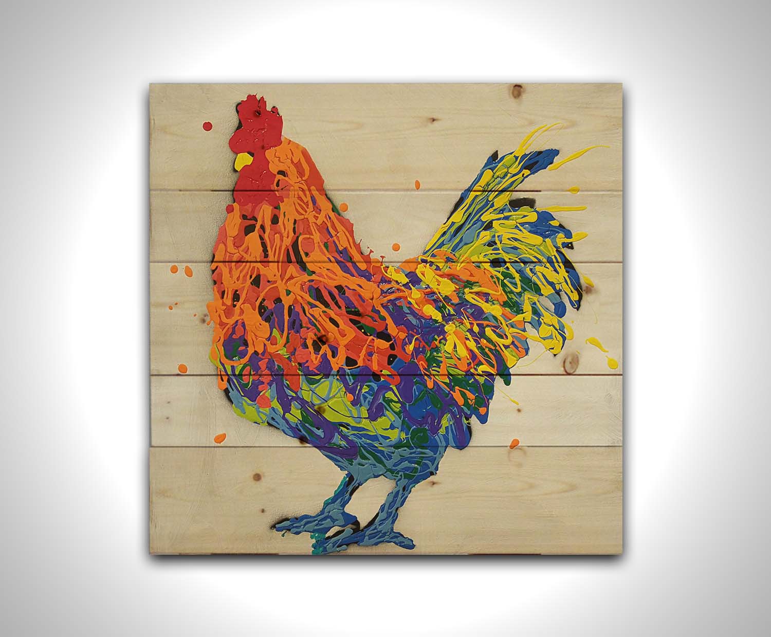 A drip painting of a multicolored rooster on a white background. Printed on a wood pallet.