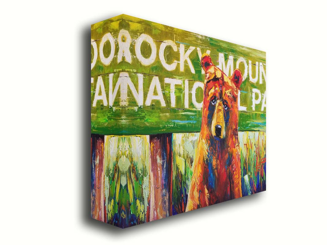 A painting of a bear standing in front of a "Rocky Mountain National Park" sign. Printed on canvas.