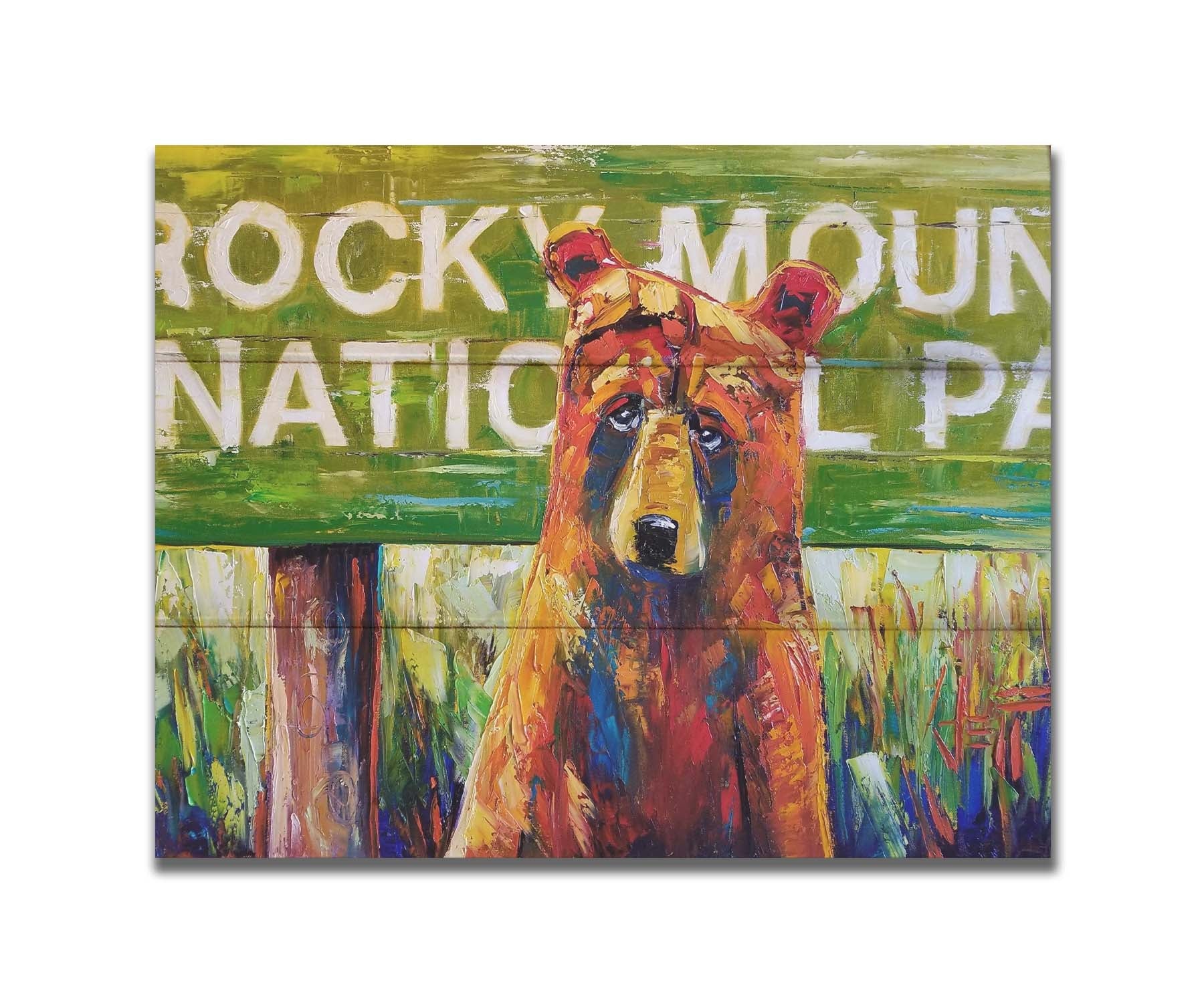 A painting of a bear standing in front of a "Rocky Mountain National Park" sign. Printed on a box board.