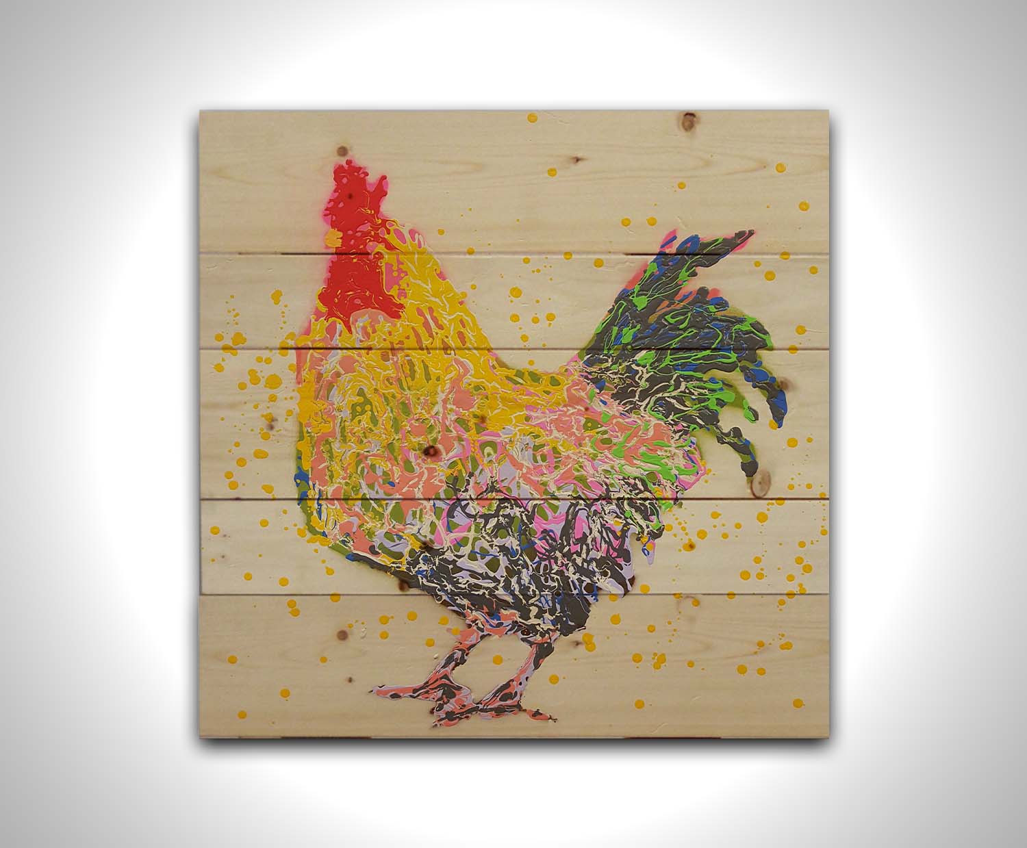 A drip painting of a gray and yellow rooster, on a white background, accented in blue, green, pink, white, and red. Printed on a wood pallet.