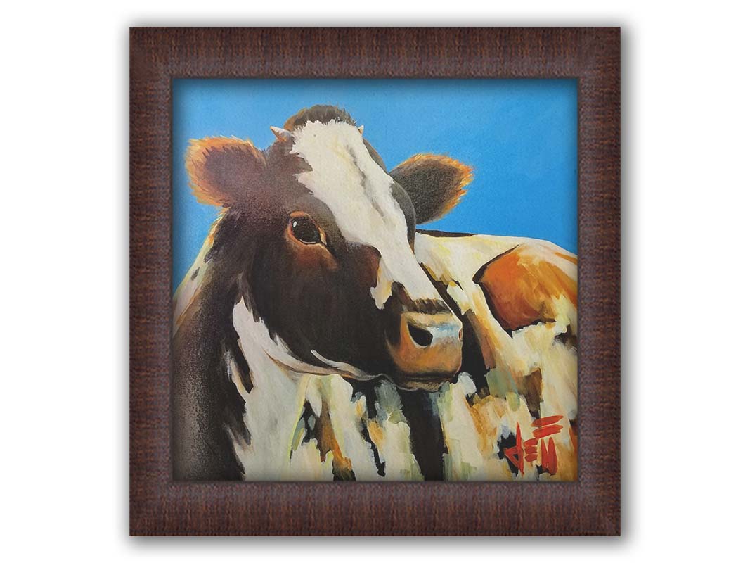 A painting of a cow basking in the sun against a bright blue background. Printed on canvas and framed.