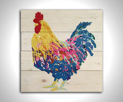 A drip painting of a yellow, blue, and pink rooster on a white background. Printed on a wood pallet.