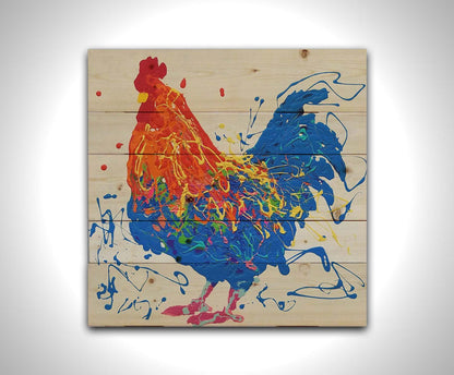 A drip painting of an orange and blue rooster on a white background, accented by yellow, green, red, and purple. Printed on a wood pallet.