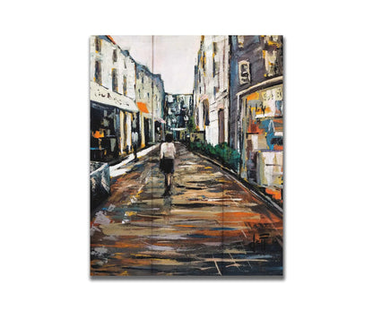 An expressive painting of a wet street lined with buildings, reflecting their colors. It is painted with highly textured, visible brushstrokes. Printed on a box board.