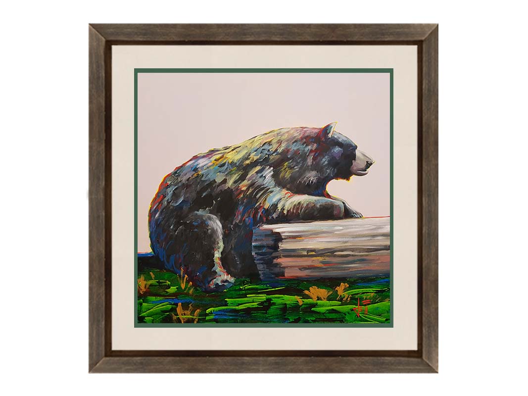 A painting of a bear accented with red, yellow, and blue sitting against a log on bright green grass with a pale pink background. Printed on paper, matted, and framed.