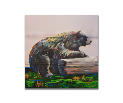 A painting of a bear accented with red, yellow, and blue sitting against a log on bright green grass with a pale pink background. Printed on a box board.