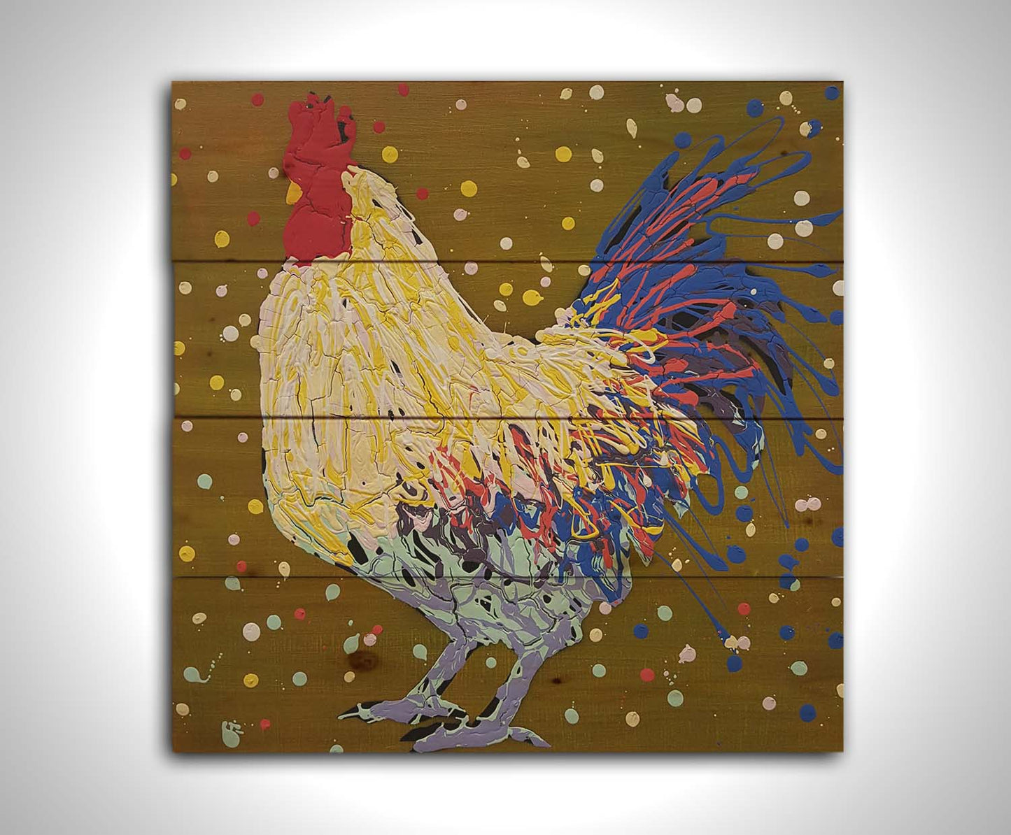 A drip painting of a rooster in white, yellow, and blue, with red accents It is posed on a gold background dotted with the colors of the rooster. Printed on a wood pallet.