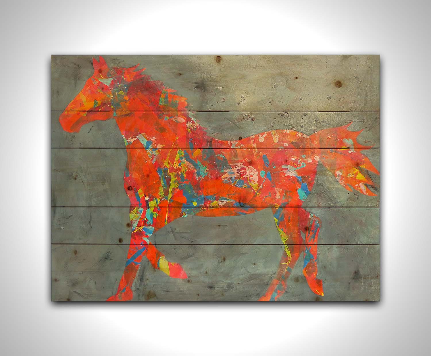 A painting of colorful patterns forming the silhouette of a horse in orange, red, blue, and yellow, against a gray background. Printed on a wood pallet.