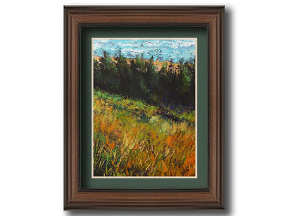 A painting of a grassy green and orange hill, lined in the distance by evergreen trees. Printed on paper, matted, and framed.