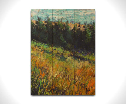 A painting of a grassy green and orange hill, lined in the distance by evergreen trees. Printed on a wood pallet.