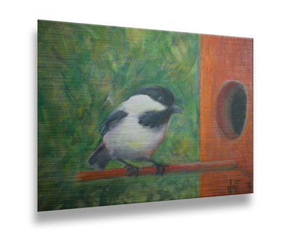 A painting of a black and white chickadee perched on an orange birdhouse, about to enter. The visible brushstrokes of the green background give the impression of foliage. Printed on metal.