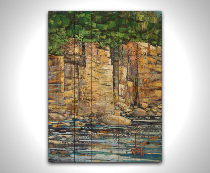 A highly textured painting with visible brushstrokes, depicting a tan cliff face bordering water. At the top of the cliffs grows a dense forest. Printed on a wood pallet.