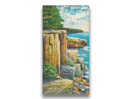 A painting overlooking a waterside clifface. Green forests grow across the tops of the cliffs, and the bright blue waters below splash against a colorful collection of rocks. Printed on canvas.