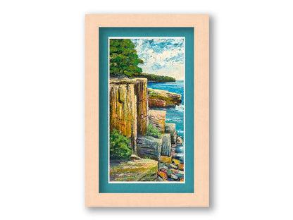 A painting overlooking a waterside clifface. Green forests grow across the tops of the cliffs, and the bright blue waters below splash against a colorful collection of rocks. Printed on paper, matted, and framed.