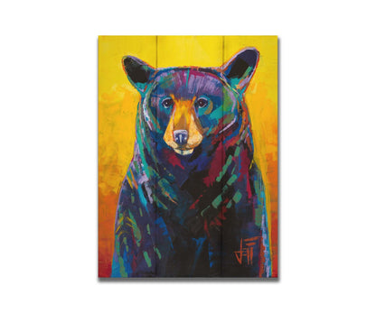 A portrait painting of a black bear, represented in colorful accents of reds, blues, greens, and purples against an orange and yellow background. Printed on a box board.