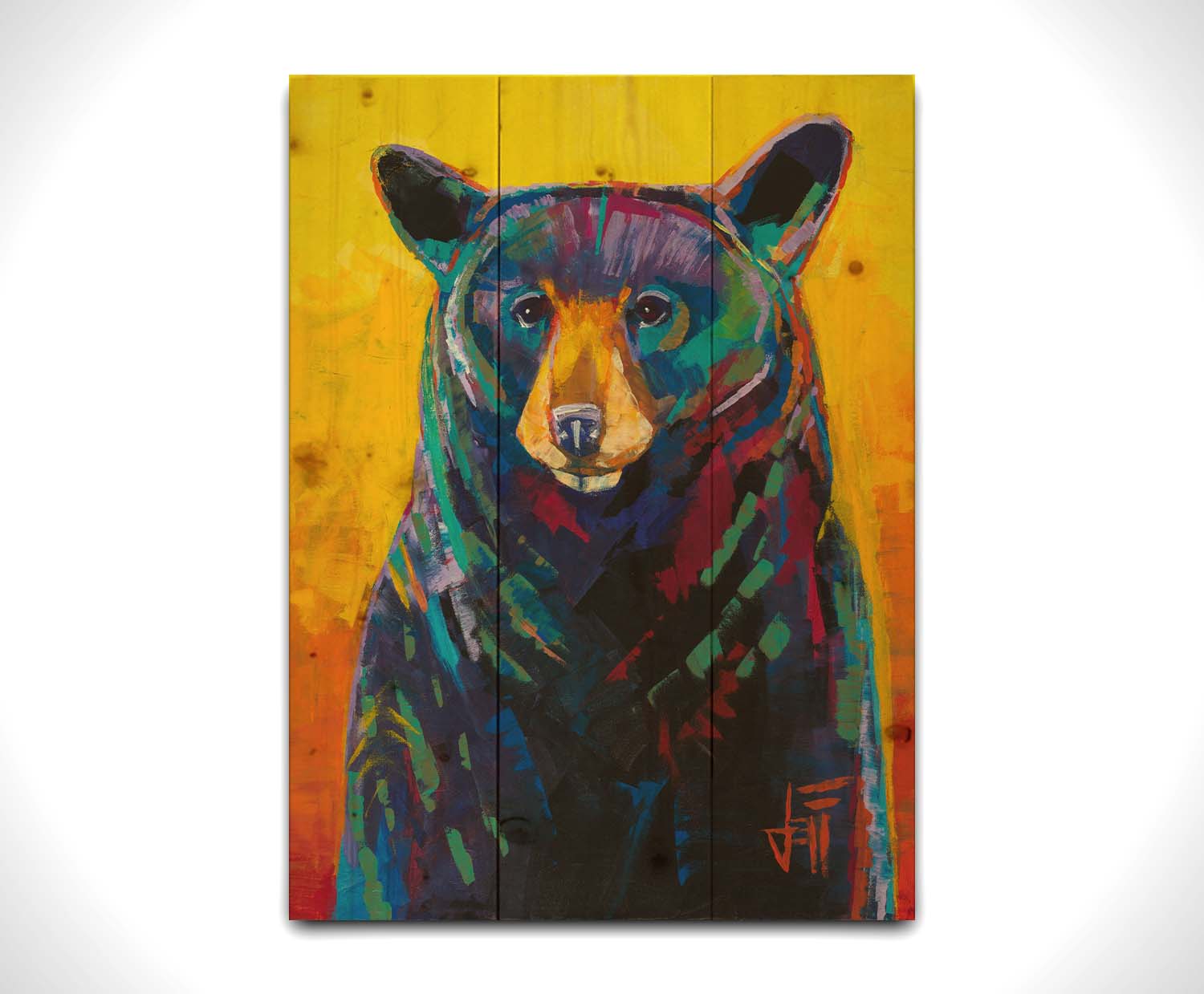 A portrait painting of a black bear, represented in colorful accents of reds, blues, greens, and purples against an orange and yellow background. Printed on a wood pallet.