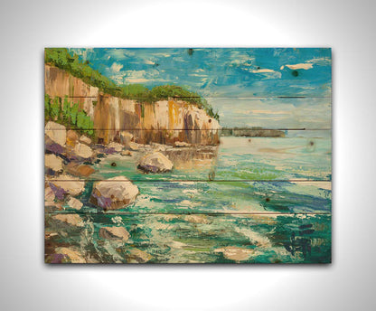 A painting of a rocky cliff overlooking clear waters on a sunny day. A vibrant green forest is growing on top of the cliffs. The teal water splashes against rocks on the shore. Printed on a wood pallet.