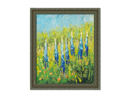 An impasto painting of blue lupine flowers in a green field, complimented by small orange flowers. Printed on canvas and framed.