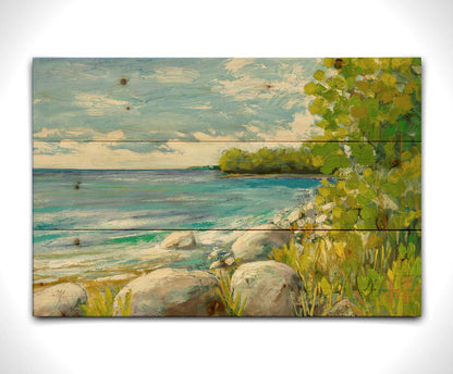 A painting of a calm bayside view. Bright green trees and foliage line the shore alongside smooth gray stones, and a blue sky with fluffy clouds reflects off smooth waters. Printed on a wood pallet.