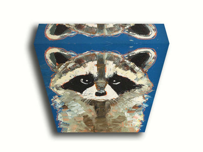 A portrait painting of a gray raccoon against a cobalt blue background. Rectangular, textured brushstrokes emphasize the fluffy textures of its fur. Printed on canvas.