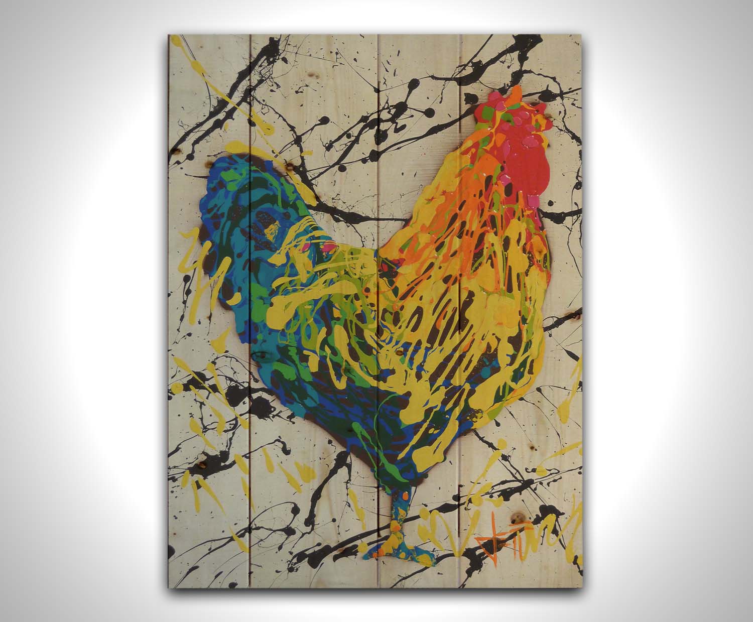 A drip painting of a rooster in red, orange, yellow, green, and blue set against a white background speckled with black and yellow. Printed on a wood pallet.