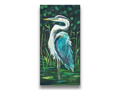 A painting of a great blue heron standing tall in a pond surrounded by vibrant foliage. Printed on canvas.